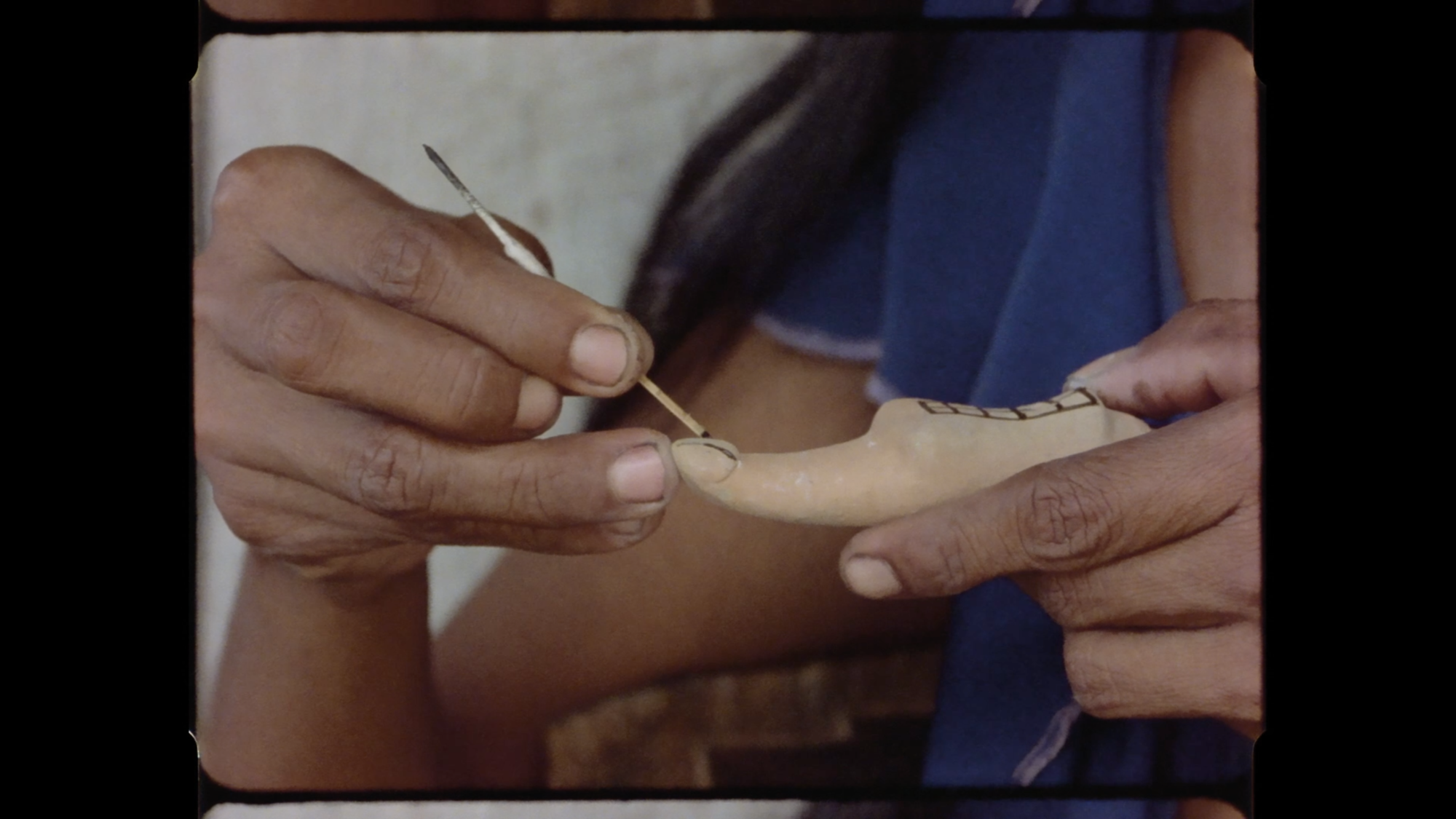 Close-up of hands painting decorative patterns on a clay figurine